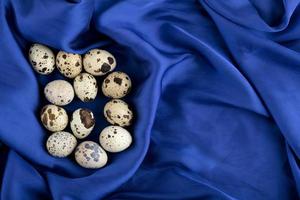 uova di quaglia fresche di fattoria su un panno di raso blu foto