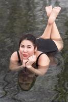 sovrappeso giovane donna nel nero un pezzo bagnarsi completo da uomo dire bugie nel all'aperto piscina a balneoterapia terme foto