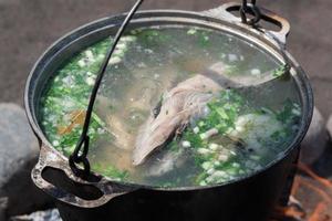 delizioso rosso salmone pesce fresco-soup cucinato nel grande giocatore di bowling su all'aperto fuoco di bivacco foto