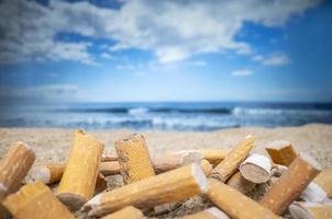 sigaretta mozziconi caduto e sinistra nel un' mucchio su un' bellissimo spiaggia foto