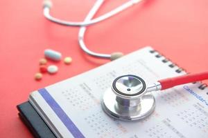 concetto di appuntamento medico con lo stetoscopio e il calendario sulla tabella rossa