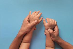 mani del bambino e del padre su sfondo blu foto