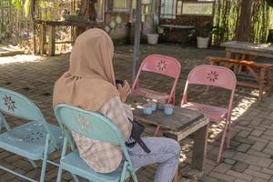 il donna aspettare su il pranzo tavolo per sua amico su il verde caffè negozio. il foto è adatto per uso per caffè negozio sfondo e media contenuto.