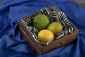 un cesto di legno con tre limoni su un panno blu foto