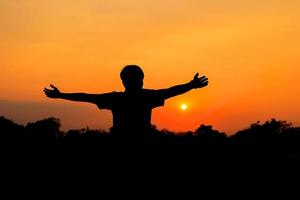 silhouette di maschio Meditare e yoga praticante con esercizio a Alba nel pubblico parco mattina foto