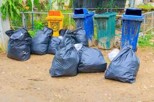 mucchio nero spazzatura Borsa plastica e quattro pattumiera sporco ciglio della strada nel il città foto