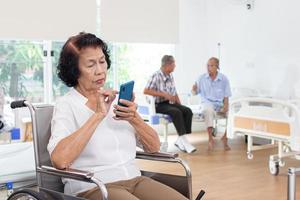 assistenza infermieristica casa cura concetto. anziano donna utilizzando un' mobile telefono. guardare a telecamera foto