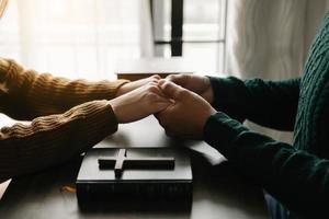 Due persone lettura e studia Bibbia nel casa e pregare insieme.studiando il parola di Dio con gli amici. foto