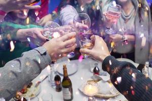 mani tintinnio bicchieri di Champagne e caramella. festeggiare un' gioioso evento con un' gruppo di le persone. foto