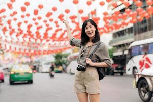 giovane asiatico donna zaino viaggiatore godendo Cina cittadina strada cibo mercato nel bangkok, Tailandia. viaggiatore controllo su lato strade. foto