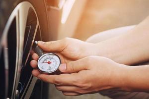 vicino su mano uomo auto parcheggio un' dai un'occhiata e gonfiare il pneumatico riempire su il aria per sicuro guida su il andare. mezzi di trasporto viaggio veicolo concetto. foto