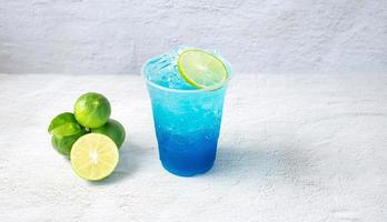 blu hawaiano bevanda nel un' plastica bicchiere e lime su bianca sfondo foto
