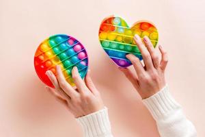 Da donna mani stampa su un' silicone arcobaleno anti stress giocattoli su un' rosa sfondo. di moda rilassamento attrezzo foto