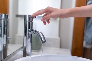 Salva acqua. donna mantiene svolta via il in esecuzione acqua nel il bagno per proteggere ambiente. greening pianeta, ridurre globale riscaldamento, Salva mondo, vita, futuro, rischio energia, crisi , acqua giorno. foto