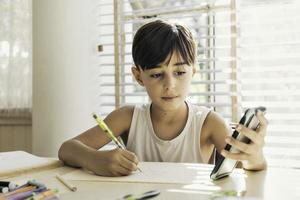 bambino disegno nel un' luminosa casa copiatura un Immagine a partire dal un' cellula Telefono. concetto di creatività, tecnologia e apprendimento. foto