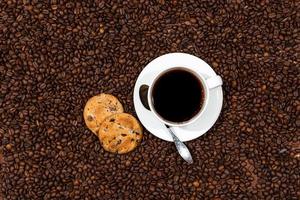 tazza di caffè bianco e biscotti sullo sfondo di chicchi di caffè foto