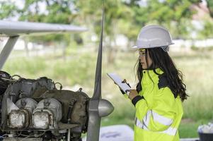 tecnico che ripara il motore dell'aereo, ingegneria aerospaziale femminile che controlla i motori degli aerei, manutenzione meccanica asiatica ispeziona il motore dell'aereo foto