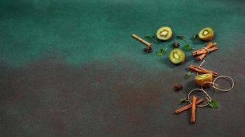 fette di fresco, succoso Kiwi su un' verde sfondo. decorato con cannella bastoni, badiano, menta le foglie. fruttato decorato sfondo foto