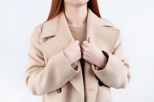 avvicinamento donna indossare beige pastello cappotto nel bianca sfondo foto