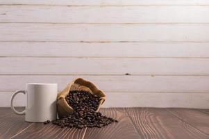 una tazza di caffè con un sacchetto di chicchi di caffè su un tavolo di legno foto