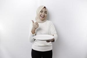 un' sorridente asiatico musulmano donna è digiuno e Affamato e Tenere e puntamento per un' piatto foto