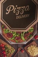pizza brasiliana con salsa di pomodoro, mozzarella, rucola, pomodori secchi e origano in una scatola di consegna foto