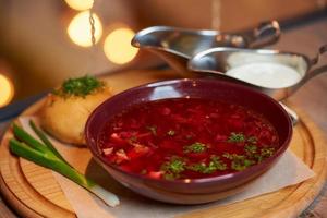 un borsch ucraino con pampushka, cipolla e panna acida su un vassoio di legno foto