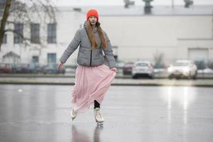 un' adolescenziale ragazza pattini su ghiaccio nel il città. foto