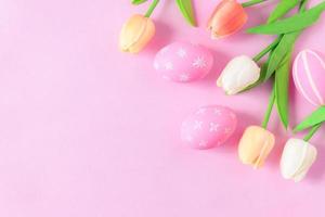 contento Pasqua vacanza saluto carta concetto. colorato Pasqua uova e primavera fiori su pastello rosa sfondo. piatto posizione, superiore Visualizza, copia spazio. foto