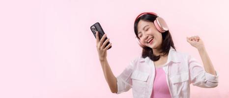 persone emozioni, stile di vita tempo libero e bellezza concetto. spensierato bella vista asiatico donna vicino occhi e danza rilassato con smartphone, ascoltando musica nel senza fili cuffie foto