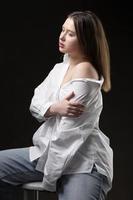 bellissimo ragazza nel un' bianca camicia su un' grigio sfondo. foto