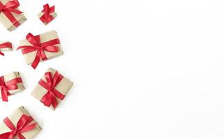 confezioni regalo avvolte in carta artigianale con nastri rossi e fiocchi su uno sfondo bianco, festosa laici piatta con spazio di copia