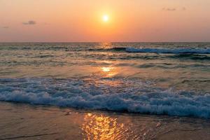 onde del mare oceano colorato durante l'alba o il tramonto con il sole sullo sfondo foto