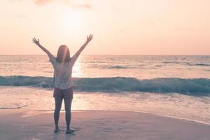 una donna alzando le mani al cielo su una spiaggia durante le vacanze estive foto