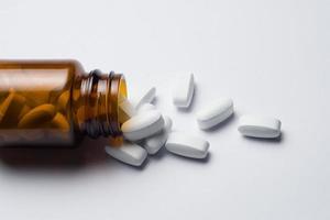 medicina pillola tavoletta con rovesciato bottiglia, bianca sfondo foto