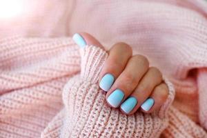 femmina mani Opaco blu pendenza manicure vicino su Visualizza su rosa a maglia maglione sfondo. foto