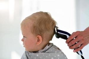 femmina mani tagliare un' bambino con un' capelli clipper nel un' parrucchiere. il primo taglio di capelli. foto