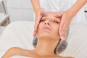 cosmetologo massaggi crema maschera in donna viso pelle per ringiovanimento, procedura nel bellezza salone foto
