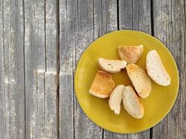 pane a fette su un piatto giallo sul fondo della tavola in legno foto