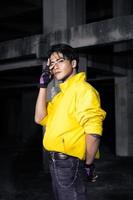 un asiatico uomo con elegante nero capelli indossare un' giallo giacca e jeans mentre in posa foto