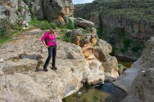 donna escursionista su il rocce Il prossimo per un' montagna fiume foto