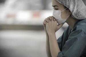 stanco depresso donna asiatica scrub infermiera indossa maschera facciale uniforme blu siede sul pavimento dell'ospedale, giovane donna medico stressato dal duro lavoro foto