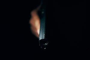 pistola nera in mano su sfondo scuro foto