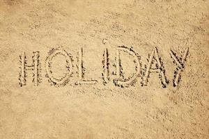 vacanza parola manoscritto su sabbia foto