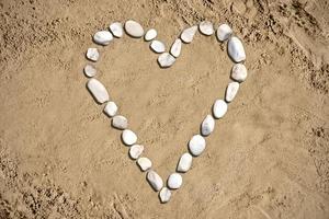 cuore forma fatto con pietre su sabbia foto