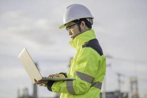 uomo asiatico ingegnere petrolchimico che lavora presso la fabbrica dell'industria degli impianti di raffineria di petrolio e gas, il controllo del lavoro dell'ingegnere dell'uomo del lavoratore delle persone presso la produzione dell'industria energetica della centrale elettrica foto