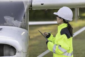 tecnico che ripara il motore dell'aereo, ingegneria aerospaziale femminile che controlla i motori degli aerei, manutenzione meccanica asiatica ispeziona il motore dell'aereo foto