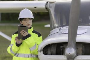 tecnico che ripara il motore dell'aereo, ingegneria aerospaziale femminile che controlla i motori degli aerei, manutenzione meccanica asiatica ispeziona il motore dell'aereo foto