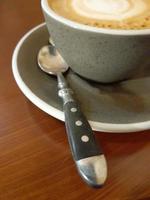 tazza di caffè su un' di legno tavolo. grigio tazza con piattino e cucchiaio foto