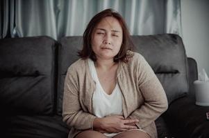 la donna asiatica malata si siede sul divano resta a casa, la donna si sentiva male, voleva sdraiarsi e riposare, febbre alta foto